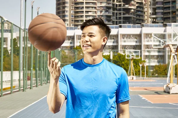 幸せな若いアジア男の指にバスケット ボールを回転 — ストック写真