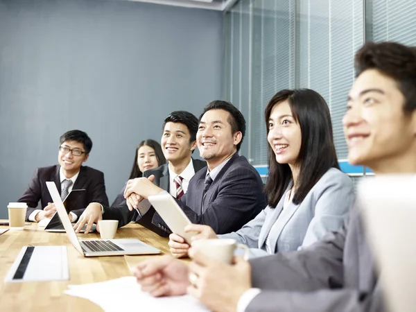 group of happy smiling asian corporate business people listening to presentation in office meeting room