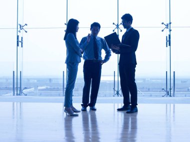 dizüstü bilgisayar kullanarak pencere tartışırken iş önünde duran üç Asya kurumsal insanlar.