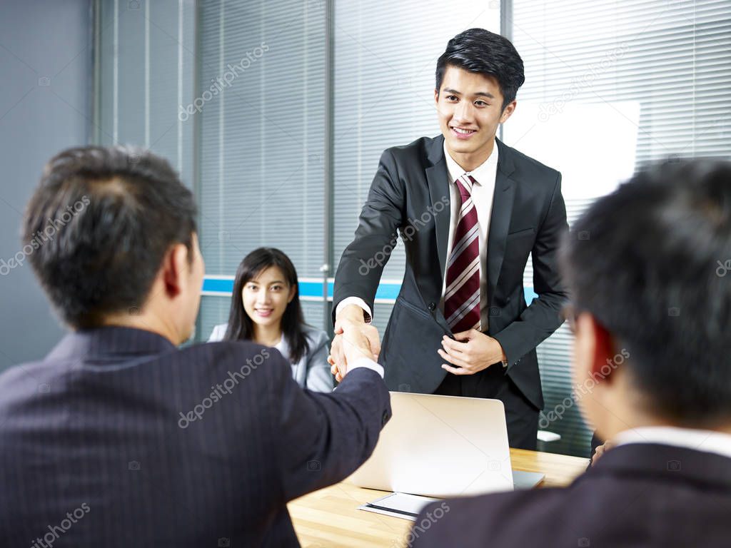 two asian business men shaking hands over meeting table before negotiation.