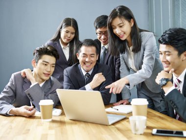 bir ekip birlikte çalışma dizüstü bilgisayar, mutlu ve gülümseyerek kullanan office Asya iş Yöneticiler.