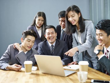 bir ekip birlikte çalışma dizüstü bilgisayar, mutlu ve gülümseyerek kullanan office Asya iş Yöneticiler.