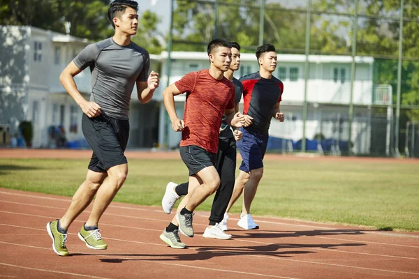 four young asian track and field athletes racing competing against each other.