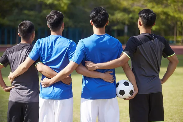 outdoor portrait of a team of young asian soccer football players, rear view