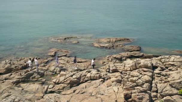 一群五个亚洲年轻人走在海边的岩石上 — 图库视频影像