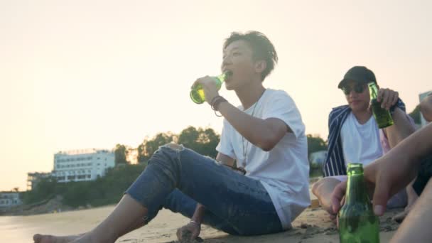 年轻的亚洲成年人坐在海滩上放松喝啤酒 — 图库视频影像