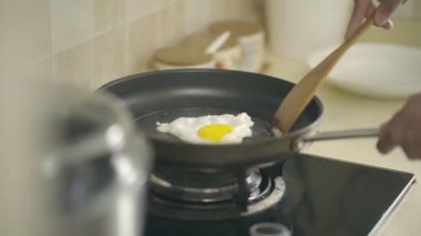 bir tavada gaz sobası kullanarak bir yumurta kızartma kişi