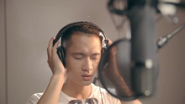 Νεαρός Ασίας Τραγουδιστής Τραγουδά Στο Στούντιο Ηχογράφησης Ακουστικά Και Μικρόφωνο — Αρχείο Βίντεο