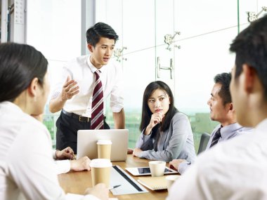Arkadaşlarınıza modern ofis toplantı sırasında konuşan genç Asya iş adamı.