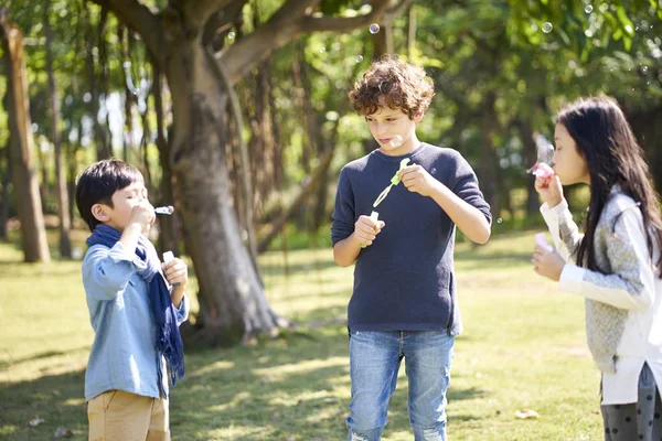 Two Asian One Italian Children Playing Outdoors Park Blowing Bubbles — Stock Photo, Image