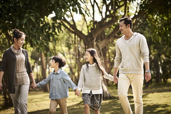 Азіатська сім'я з двома дітьми, що ходять розслабляючись у парку — стокове фото