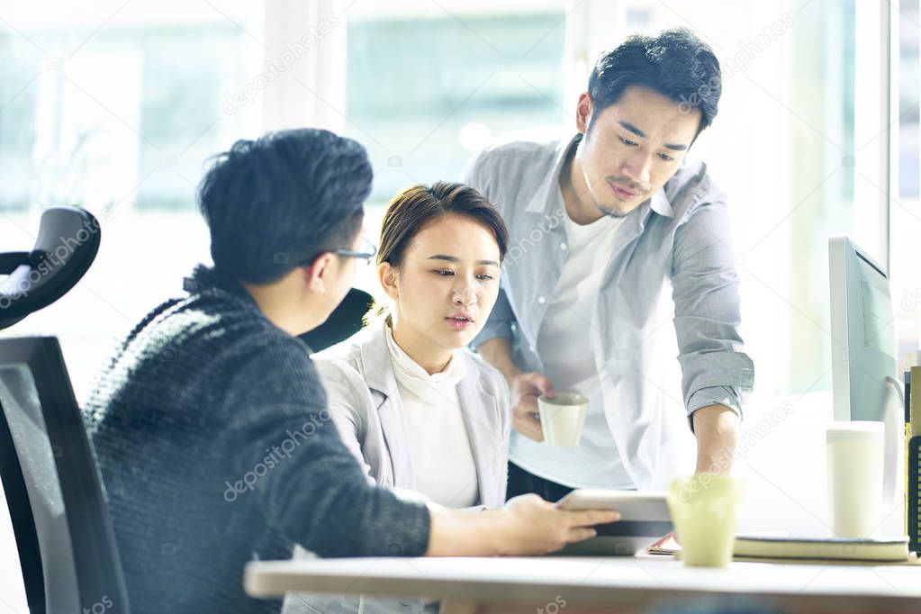 three young asian entrepreneurs discussing business in office