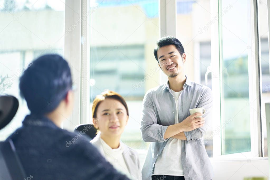 three young asian business people chatting in office