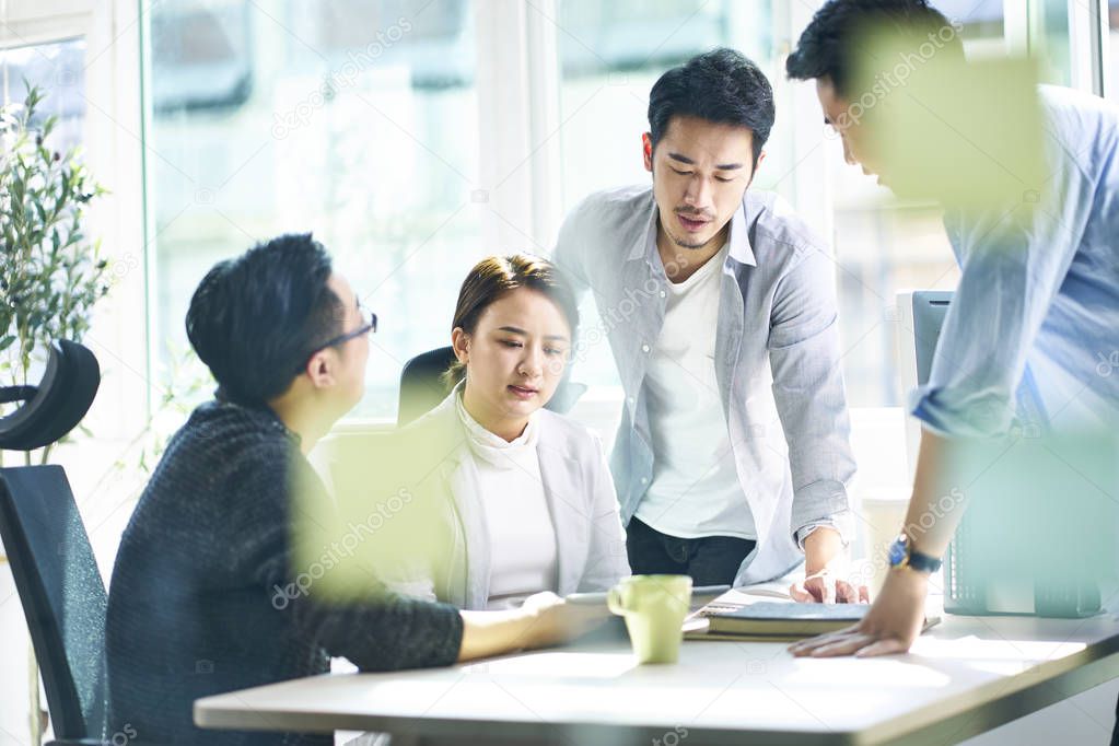 group of four asian business people working together in office