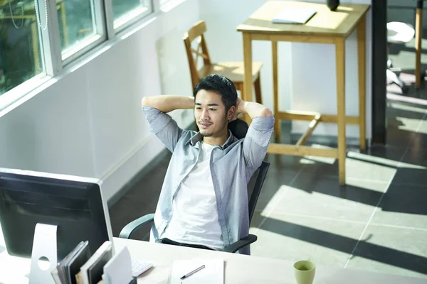 Junger asiatischer Mann schaut im Büro auf Computer — Stockfoto