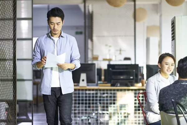 Young asian entrepreneur looking at document — Stockfoto