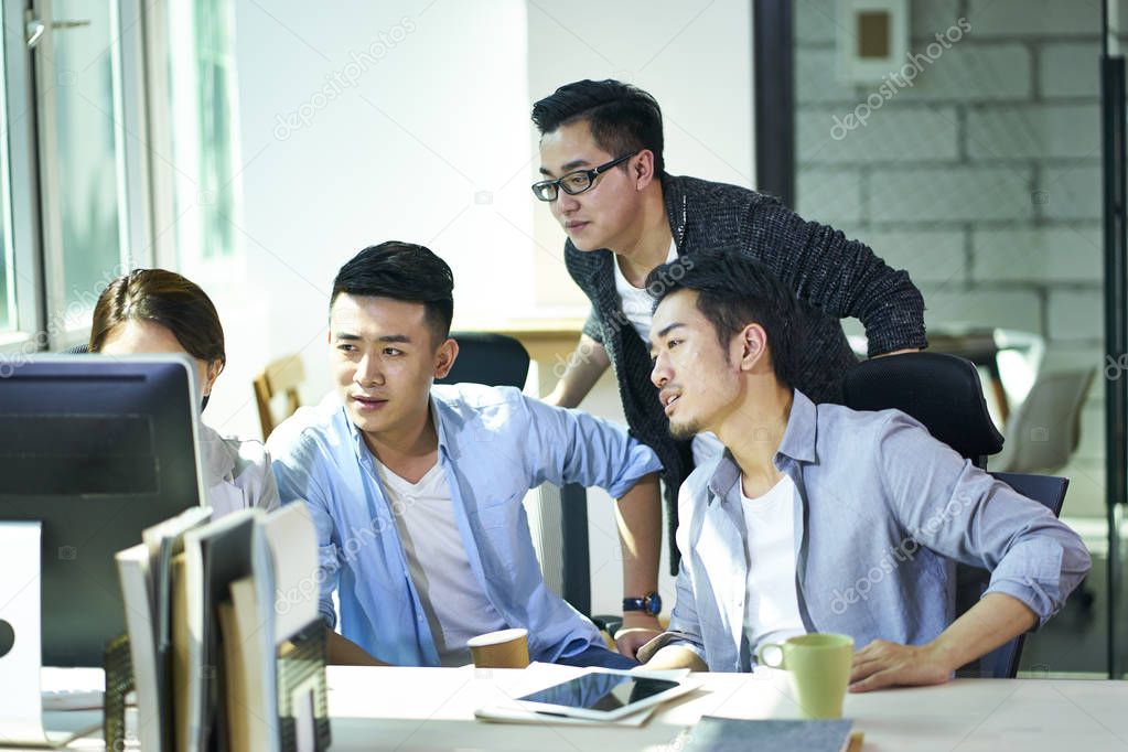 four young asian entrepreneurs discussing business in office