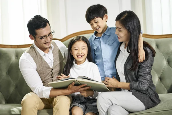 Aziatische moeder en vader en twee kinderen lezen boek samen — Stockfoto