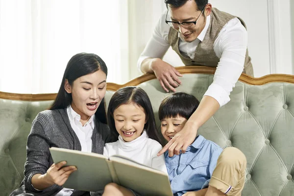 Mutter und Vater mit zwei Kindern lesen gemeinsam Buch — Stockfoto