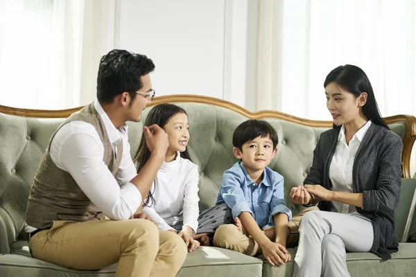 Asiatische Eltern und zwei Kinder plaudern zu Hause — Stockfoto