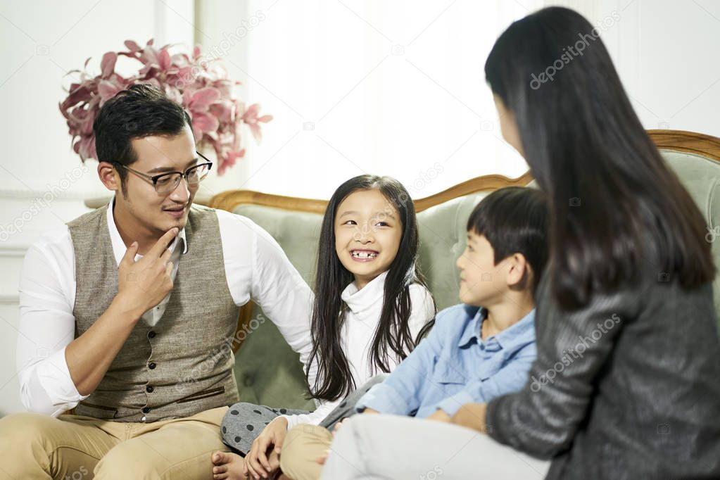 asian mother and father and two children chatting at home