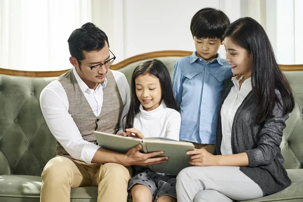 Asiatische Familie mit zwei Kindern liest gemeinsam Buch — Stockfoto