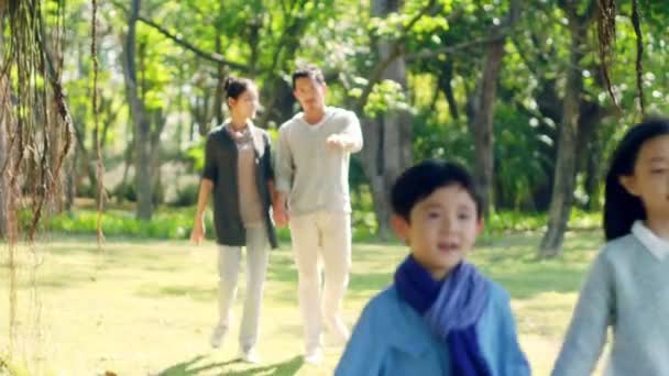 Азиатские Родители Смотрят Двух Детей Гуляющих Открытом Воздухе Парке — стоковое видео