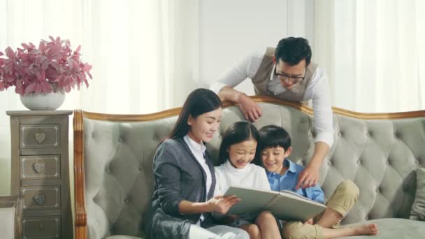 Asian Family Two Children Reading Book Together Living Room Home — Stock Video