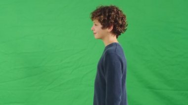 yeşil arka plan aleyhine gülümseyen küçük beyaz bir çocuğun yan görünümü