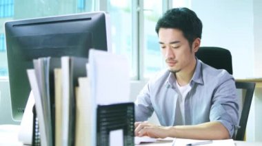 ofis masaüstü bilgisayar kullanarak çalışan genç Asya iş adam