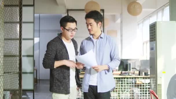 Két Fiatal Ázsiai Üzletember Megbeszéli Eladási Jelentést Kisvállalati Irodában — Stock videók