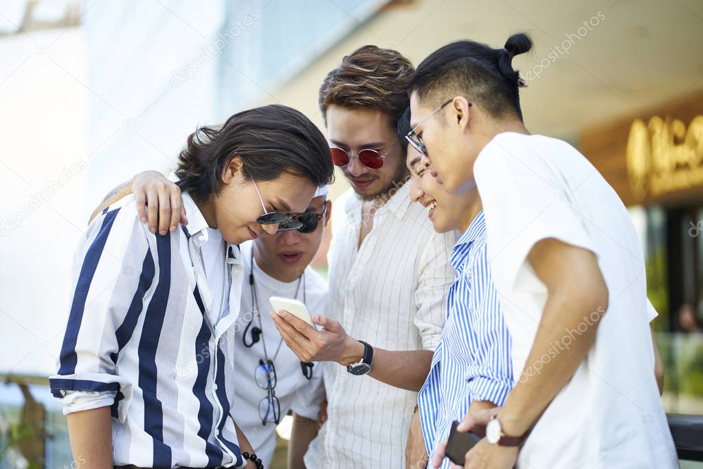 young asian adult men looking at cellphone together