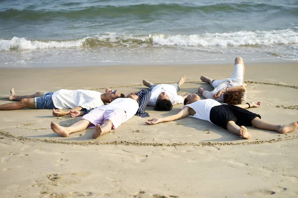 group of asian men lying on beach