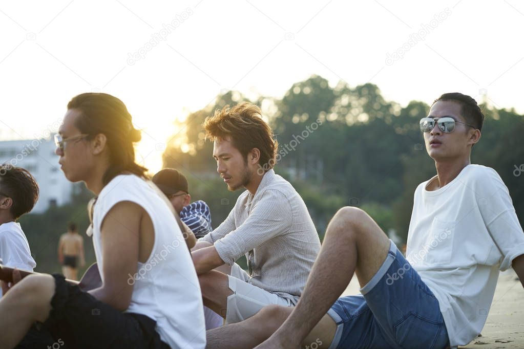 group of asian men sitting on beach