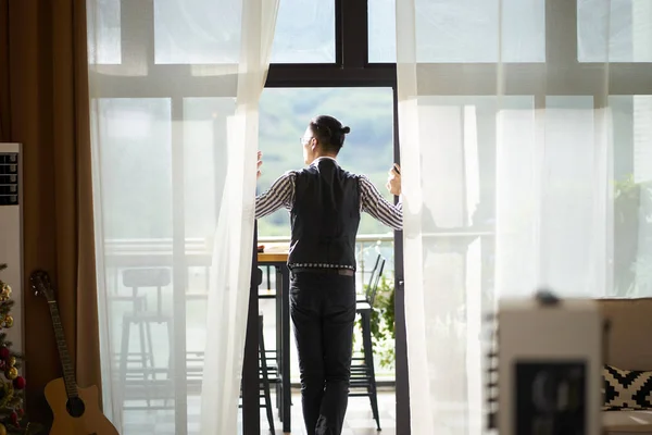 Rear view of a young asian man standing on patio — Stock Photo, Image