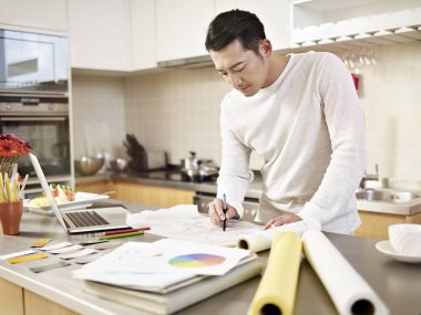 Genç Asyalı serbest mızrak tasarımcısı evde çalışıyor.