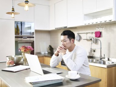 Genç Asyalı adam evden çalışıyor.