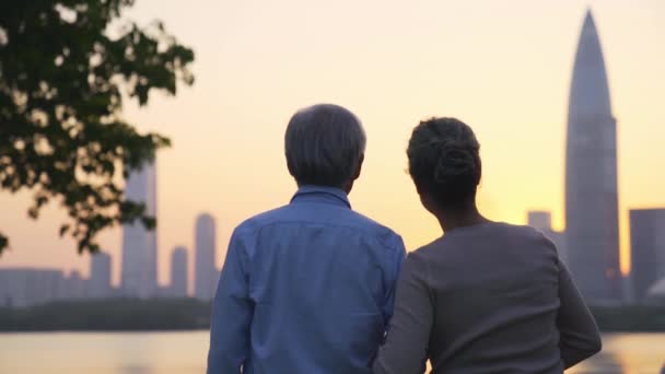 Asyalı Yaşlı Çiftin Şehrin Ufuk Çizgisinde Nehir Kenarında Gün Batımını — Stok video