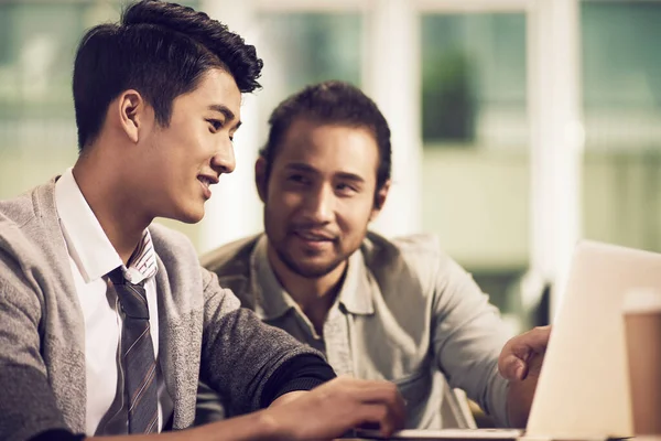 Two Young Asian Entrepreneurs Discussing Business Using Laptop Computer Office — Stock Photo, Image