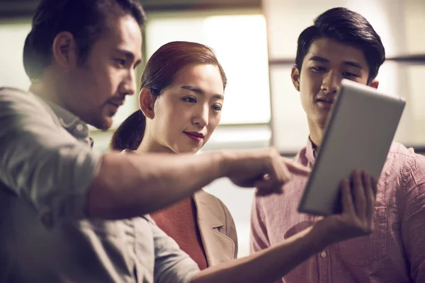 Tres Jóvenes Empresarios Asiáticos Trabajando Juntos Oficina Mirando Tableta Digital —  Fotos de Stock