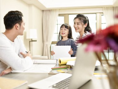 Bir çocuklu genç Asyalı aile mutlu ve neşeli bir şekilde evde kalıyor.