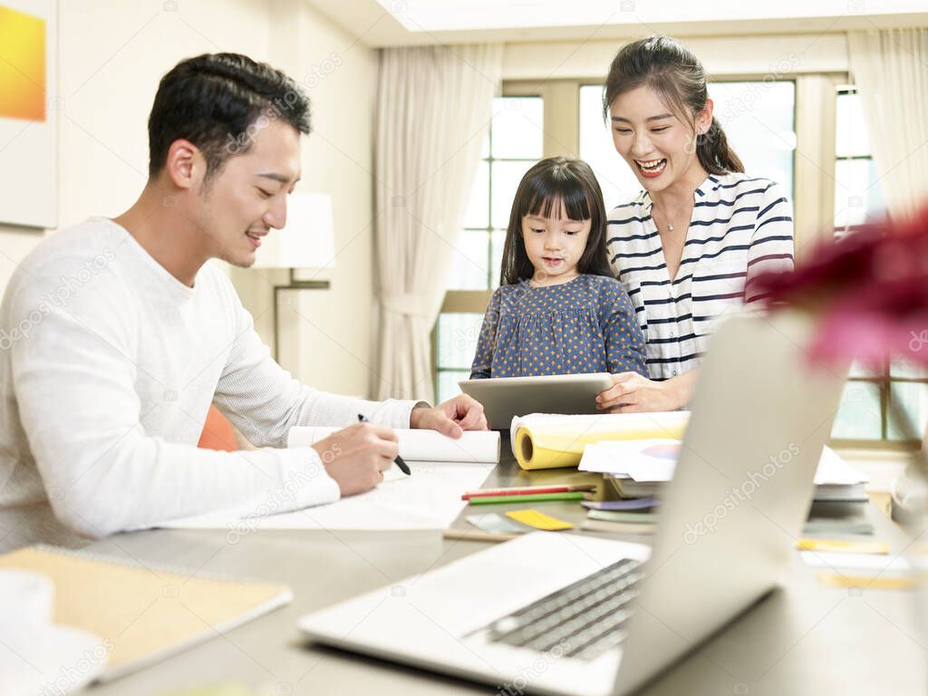 young asian family with one child staying home happy and cheerful (artwork in background digitally altered)