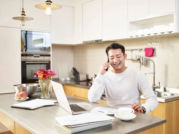 Ung Asiatisk Affärsman Sitter Köksbänk Arbetar Hemma Pratar Mobiltelefon Skrattar — Stockfoto