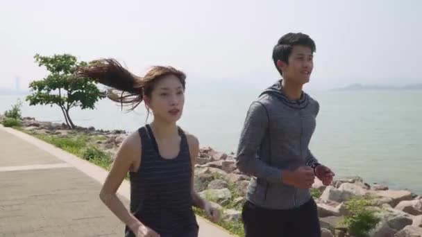 海辺の公園でジョギングをしているアジアの若いカップル — ストック動画