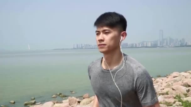 Азиатский Молодой Человек Слушая Музыку Время Бега Трусцой Открытом Воздухе — стоковое видео
