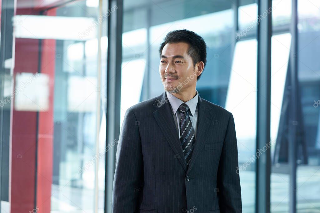 successful asian businessman corporate executive walking in company lobby