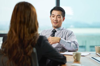 Asyalı iş kadını ve işadamı ofiste iş konuşuyorlar