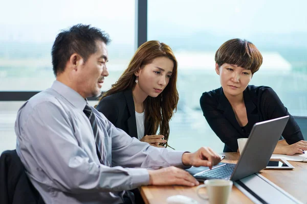 three asian corporate executives man and woman meeting in office using laptop computer