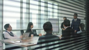 Asyalı yönetici modern ofis konferans odasında personel toplantısında yeni bir takım üyesini tanıtıyor.
