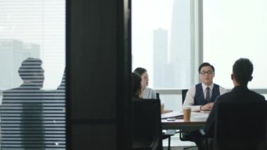 Asyalı iş adamlarından oluşan bir grup modern ofis konferans salonunda toplanıyor.